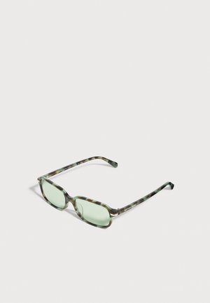 Lunettes Michael Kors façon écaille de tortue, avec une monture rectangulaire et des verres vert pâle, sur un fond clair.