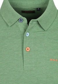 Groene katoenen polo met een textuur oppervlak. Bevat een gekraagde hals, drie knopen in blauw, groen en oranje, en een geborduurd logo.