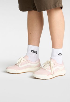 Rosa sneakers med vita accenter, mesh och syntetiskt material, rund tå, låg design, parat med vita strumpor som har en svart logotyp.