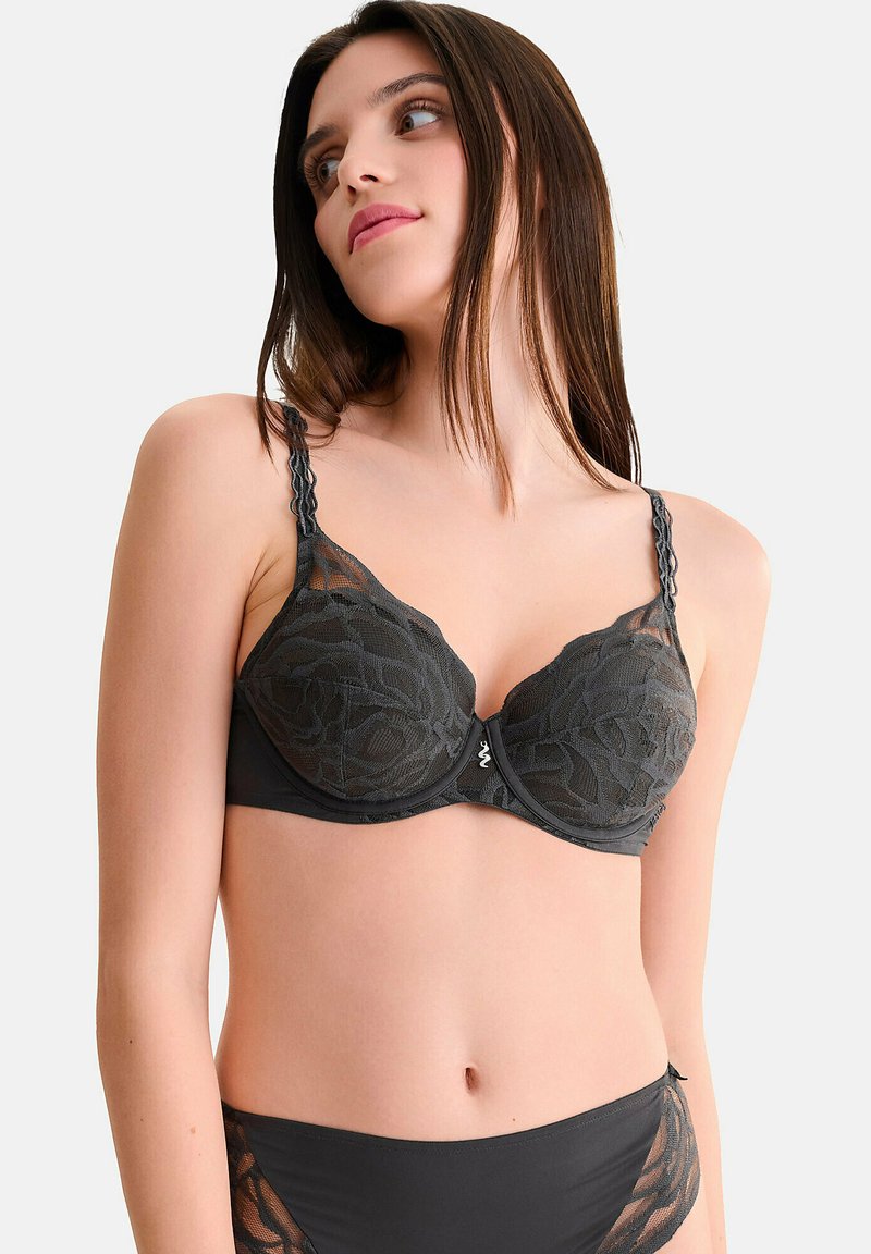 Zwarte kanten bh met bloemenpatroon, gewatteerde cups en een golvende rand. Verstelbare bandjes en een slank ontwerp met details van een sluiting aan de voorkant.