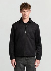 Veste en daim noir avec fermeture éclair à l'avant, petit col, deux poches poitrine et coupe décontractée. Finition texturée et palette de couleurs monochrome.