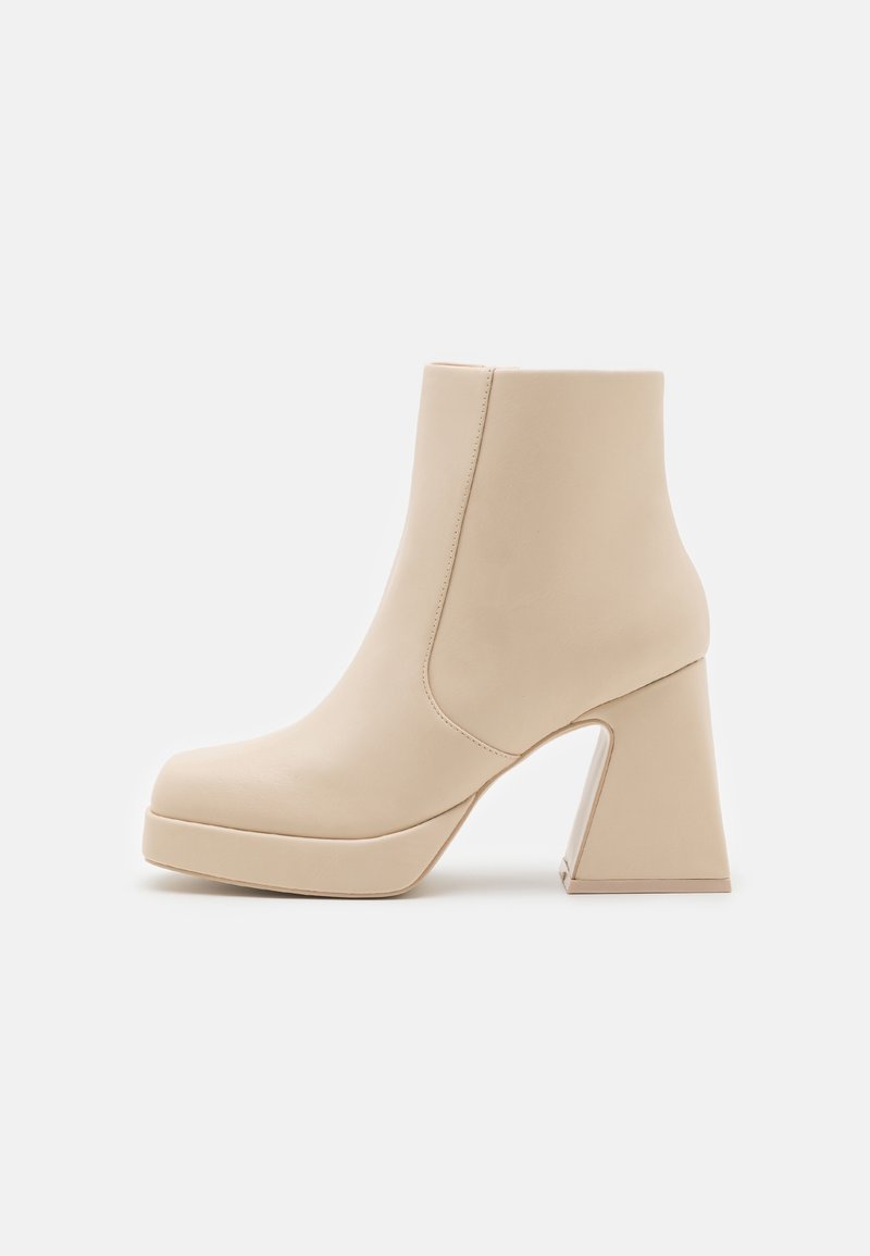 Bottine beige à talon haut épais et semelle plateforme, finition en cuir lisse, fermeture éclair latérale et bout arrondi.