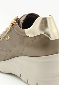Baskets en cuir tan avec des accents dorés métalliques, des zippers décoratifs et une épaisse semelle beige. Présente des détails cousus sur la tige.
