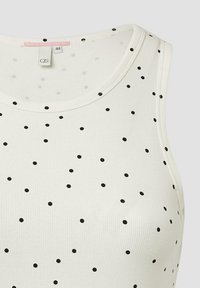 Witte geribde tanktop met kleine zwarte stippen over de hele stof. Ronde halslijn en mouwloos ontwerp. Etiket zichtbaar binnenin de kraag.