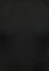 Μαύρη ριγέ μπλούζα από υφασμάτινη ύφανση, με κατακόρυφες και διαγώνιες ρίγες, και υφή. Εφαρμόζει στο σώμα χωρίς ορατά μεταλλικά ή διακοσμητικά στοιχεία.