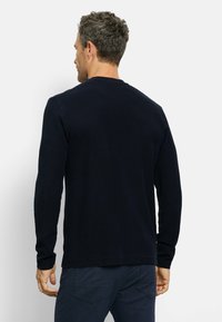 Marineblaues Langarmshirt aus strukturiertem Material, mit Rundhalsausschnitt und gerippten Bündchen. Einfaches Design ohne sichtbare Logos oder Muster.