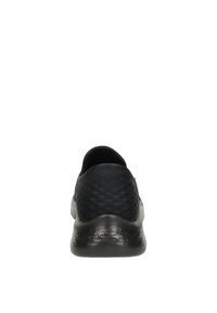 Scarpa sportiva nera con texture, vista dal retro, dotata di suola ammortizzata e collo basso.