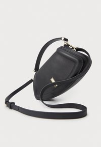 Μαύρη δερμάτινη τσάντα χιαστί με τριγωνικό σχήμα, χρυσές μεταλλικές λεπτομέρειες και λεπτό λουράκι. Λείος υφασμάτινος σχεδιασμός με μινιμαλιστική αισθητική.