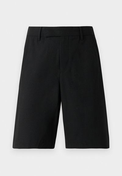 Sorte skræddersyede shorts i knælængde med bæltestropper, glat front og sidelommer imod en ensfarvet lys baggrund.