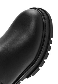 Black leather ankle boot with a smooth texture, rounded toe, and rugged rubber sole featuring a pronounced tread pattern.