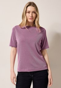 T-shirt viola a maniche corte con scollatura rotonda, caratterizzato da una texture liscia e una vestibilità comoda, abbinato a jeans scuri.