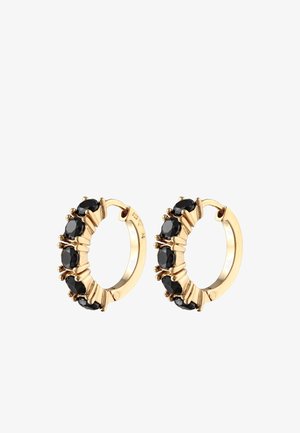 Boucles d'oreilles en or en forme de anneau, ornées d'une rangée de pierres noires facettées, maintenues par des griffes et affichant une surface texturée. Le diamètre présente de subtils courbes.