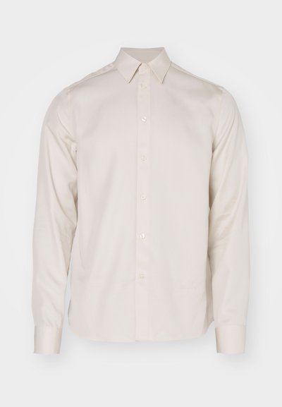 Chemise à manches longues, boutonnée, en tissu beige doux. Présente un col pointu, un ourlet droit et un détail de logo subtil près de l'ourlet.