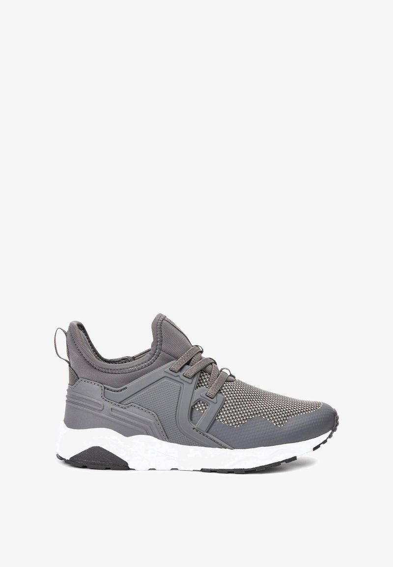 Baskets athlétiques grises avec tige en mesh et synthétique, lacets gris, languette de traction au talon, et semelle épaisse blanche avec semelle extérieure noire.