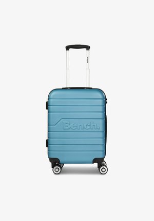 Blauwe harde koffer met reliëf "Bench." logo, gestructureerd oppervlak, uitschuifbare handgreep en vier witte wielen voor mobiliteit.