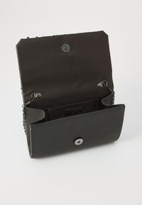 Clutch rettangolare nera con una texture liscia, dotata di chiusura a scatto metallica e tracolla a catena. L'interno presenta più scomparti.