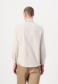 Lys beige stripete langermet skjorte med knappede mansjetter og avrundet kant, laget av myk stoff. Minimalistisk design, ingen synlig merkevare.