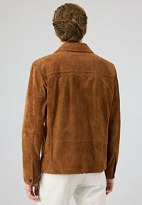 Bruine suede jas met een klassieke kraag, naadloos ontwerp en knopenmanchetten. Vlotte textuur en subtiele stiksels op de achterkant.
