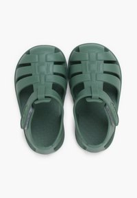 Chanclas de goma verdes con diseño de punta cerrada, correas abiertas, patrón de suela elevada y una correa trasera para un ajuste seguro.