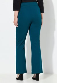 Pantalones acampanados en color verde azulado, hechos de una tela elástica con una textura suave, que cuentan con una cintura alta y una costura sutil en el dobladillo.