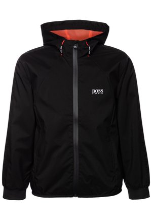 Veste noire zippée à capuche avec doublure intérieure rouge, poignets élastiques, poches latérales et logo blanc "BOSS HUGO BOSS" sur la poitrine.