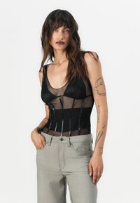 Černý síťový body s průhlednými panely, s V výstřihem a elegantními vertikálními akcenty. V kombinaci s světle šedými džíny s vysokým pasem.