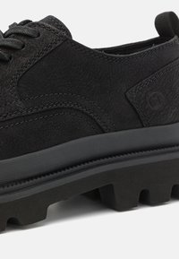 Schwarzer Lederschuh mit strukturiertem Obermaterial, geschichteter Bauweise und Gummisohle mit ausgeprägtem Profil. Dezente Nähte und Logo-Akzent.