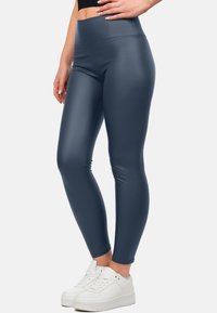 Navy hoge taille leggings gemaakt van een gladde, rekbare stof, met een naadloos ontwerp en gecombineerd met witte sneakers.