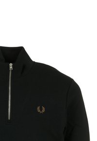 Sudadera negra con cremallera y cuello alto, hecha de un tejido suave, que presenta un pequeño emblema bordado en dorado en el lado izquierdo del pecho.