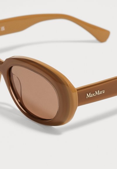 Lunettes de soleil ovales marron avec montures épaisses et verres teintés, avec le logo MaxMara sur la branche.
