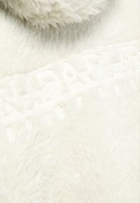 Vit konstpäls med en mjuk, fluffig textur och en prägling med ett geometriskt mönster. Mysig och lätt konstruktion.