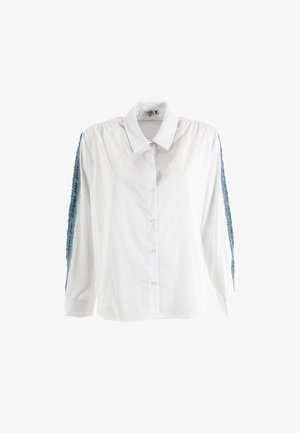 Camisa blanca de manga larga con cuello estructurado, que presenta acentos azules texturizados a lo largo de las mangas y cierre de botones al frente.