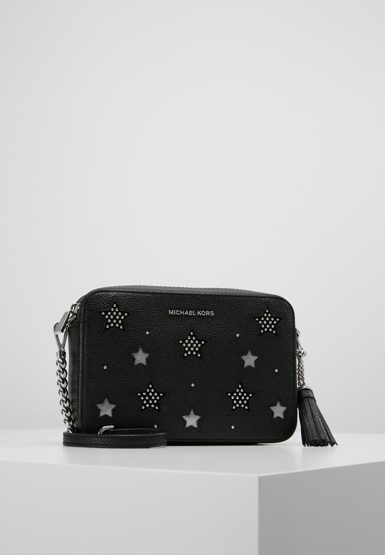 Czarna skórzana torba na ramię z ozdobami w kształcie gwiazd, srebrnymi ćwiekami, łańcuszkowym paskiem oraz frędzlami. Logo marki umieszczone z przodu.