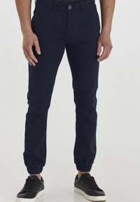 Marine joggebukser laget av bomull med elastisk midje og mansjetter, med side lommer og en knappelukking foran.