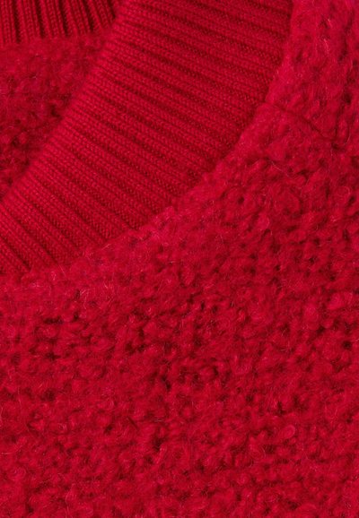 Maglione rosso lavorato a maglia con una finitura strutturata e pelosa, dotato di un colletto a coste nella parte superiore. Tessuto morbido e spesso.
