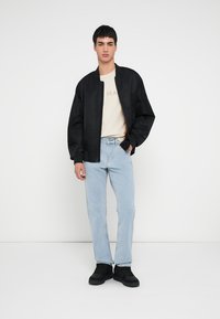 Must musta bomberjakk, kreemikas t-särk kirjaga "JEANS", hele sinised teksad, mustad tennised. Lihtne disain, lõdvestunud istuvus, vabaaja stiil.