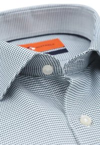 Patroontas T-shirt met een lichtblauw en donkergroen geometrisch patroon, gemaakt van katoen, met een kraag met knopen en een enkele witte knoopdetail.