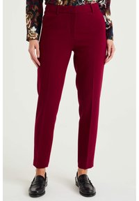 Burgundy byxor med slim fit, med flat front, bälteshällor och sidofickor, kombinerade med svarta loafers och en mönstrad topp.