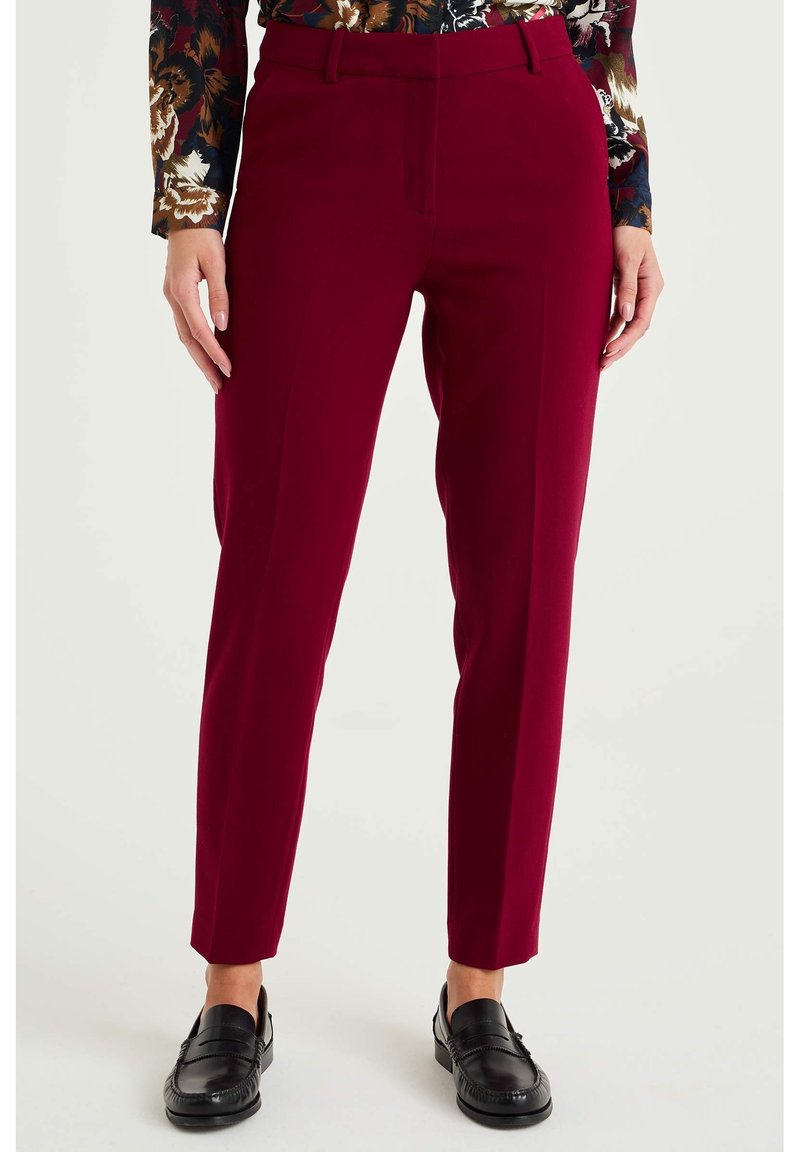 Burgundy byxor med slim fit, med flat front, bälteshällor och sidofickor, kombinerade med svarta loafers och en mönstrad topp.