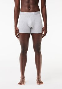 Gray cotton boxers with a soft waistband featuring the "LACOSTE" logo in light gray. Smooth texture and fitted design.