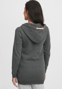 Grå hettegenser med teksturert finish, justerbar snor, og en faux skinn detalj ved halsen. Lange ermer og en avslappet passform.