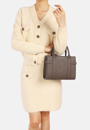 Abito cardigan beige con dettagli a bottoni e tasche, abbinato a una piccola borsa grigia texturizzata con logo impresso e forma strutturata.