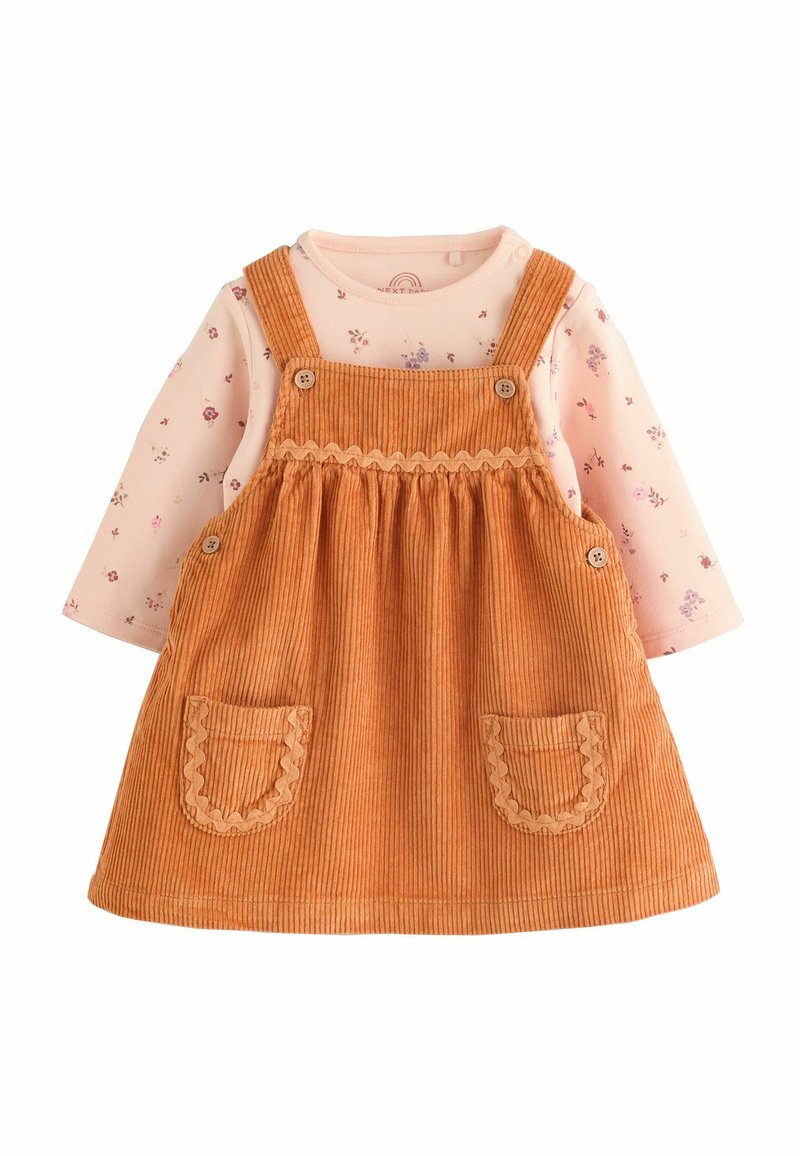 Robe en velours côtelé orange avec des poches à bords festonnés, associée à une chemise à manches longues rose ornée de petits motifs floraux.