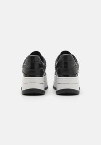 Sneakers neri con una parte superiore in pelle liscia, suola platform rialzata e borchie decorative. Presentano una suola di contrasto bianca e nera.