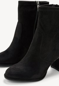 Černé semišové kotníkové boty s špičatou špičkou, bočním zipem a silnou podpatkem. Hladká textura, jednoduchý design a švy.