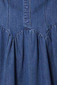 Denim odjevni predmet s dugim kopčanjem sprijeda, nabranom teksturom u struku i tamnoplavom nijansom s glatkom površinom.