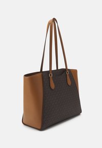 Bruine en donkergepatenteerde leren tote bag met twee lange handvatten en gestructureerde rechthoekige vorm tegen een witte achtergrond.