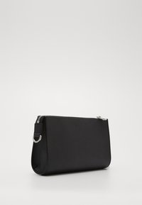 Pochette en cuir noir avec une finition texturée, fermeture éclair et quincaillerie en argent. Dispose d'une petite boucle sur le côté pour attacher des accessoires.