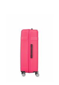 Jasnoróżowa walizka z twardą skorupą stojąca pionowo na czterech kółkach obrotowych z czarnym bocznym uchwytem na białym tle.