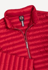 Punane tikitud jope hõbedase lukuga, mis on osaliselt avatud, püstkraega ja kaelas sees must silt kirjadega "Colmar Originals".